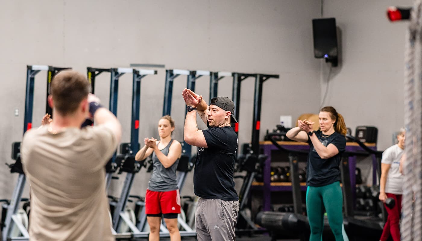 A coach leading the whole class through an arms-overhead warm-up