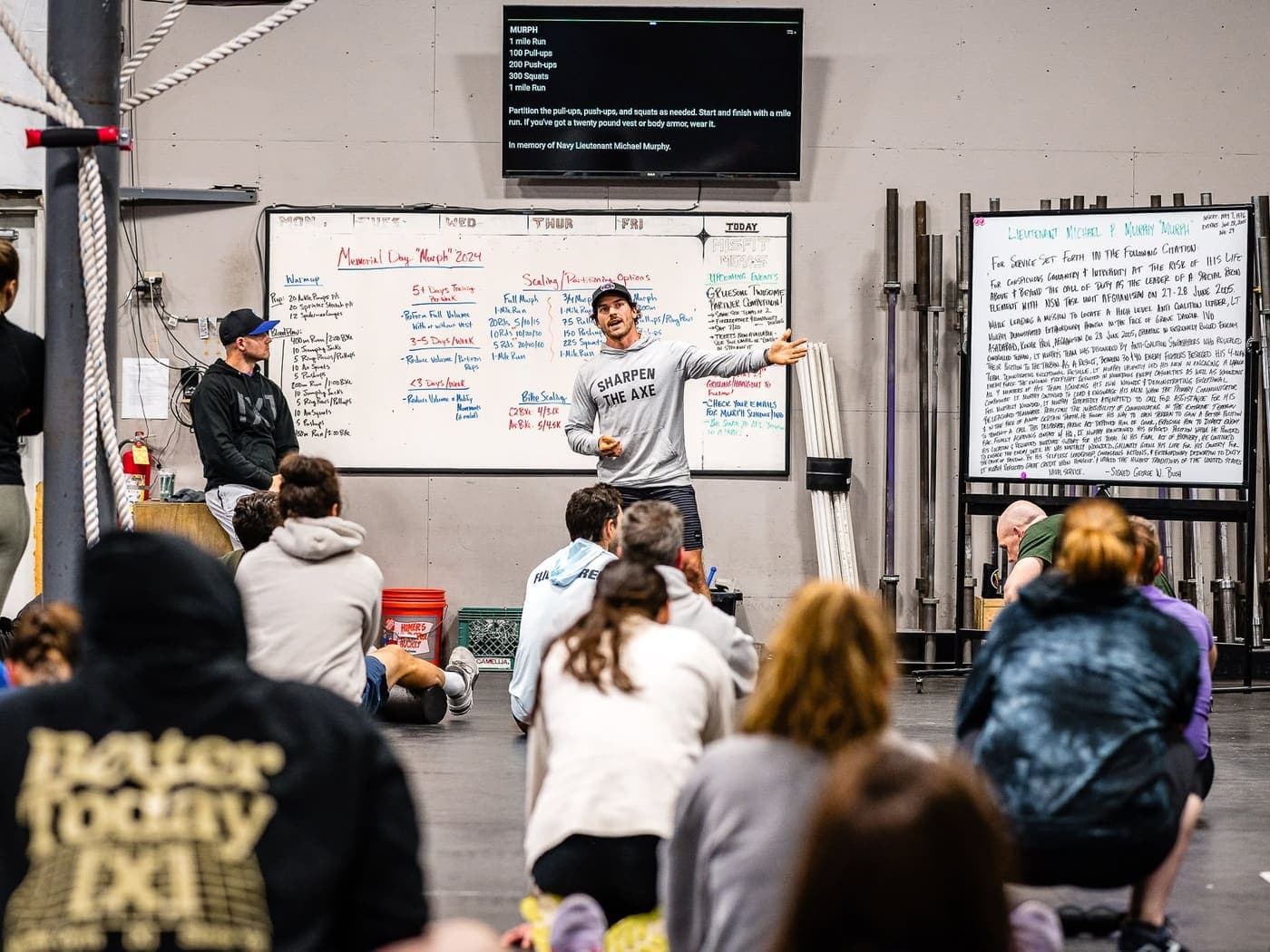 A coach walking the seated class through the day's workout at the whiteboard