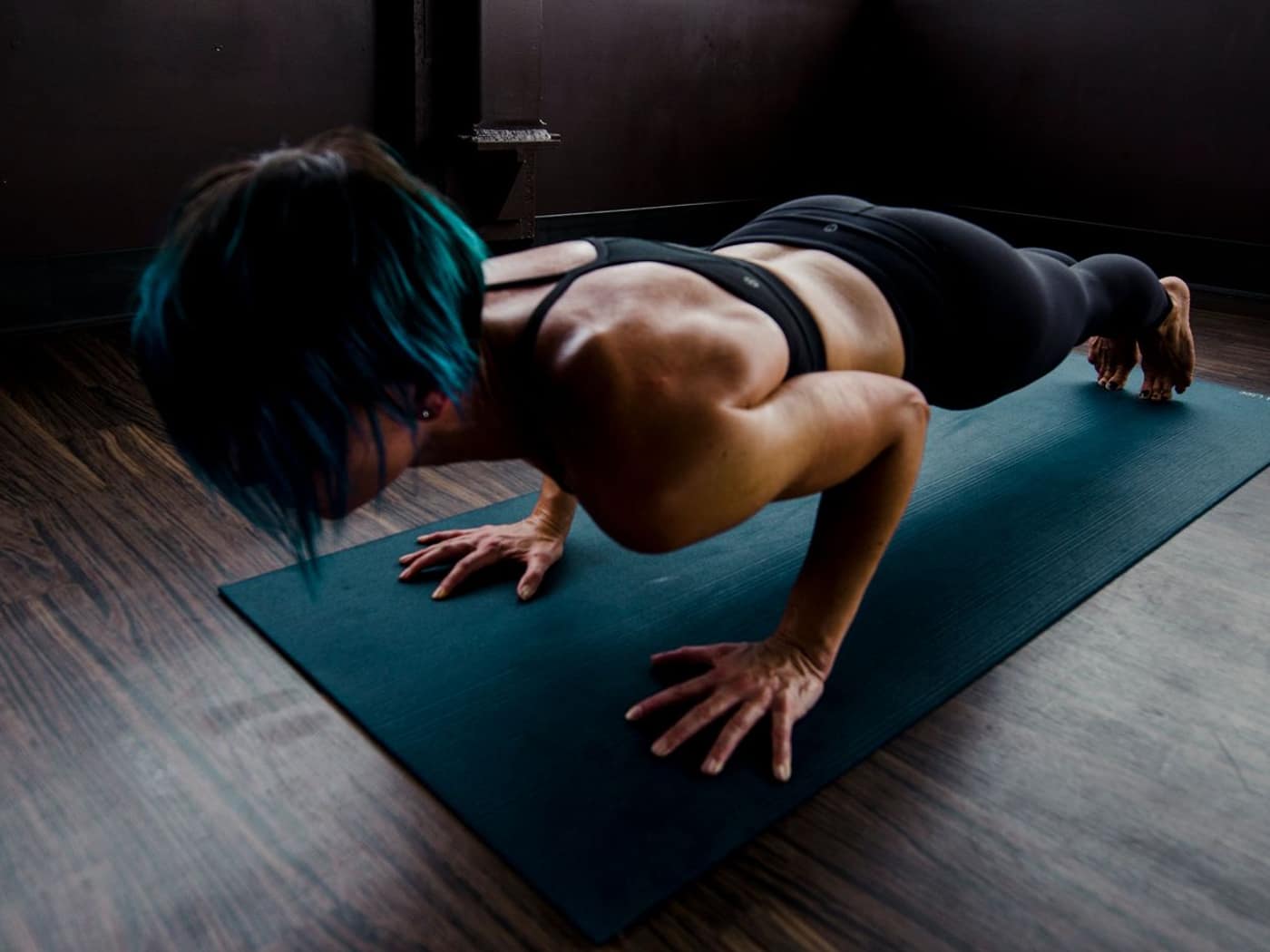 Athlete holding a push-up position on a mat in a quiet gym