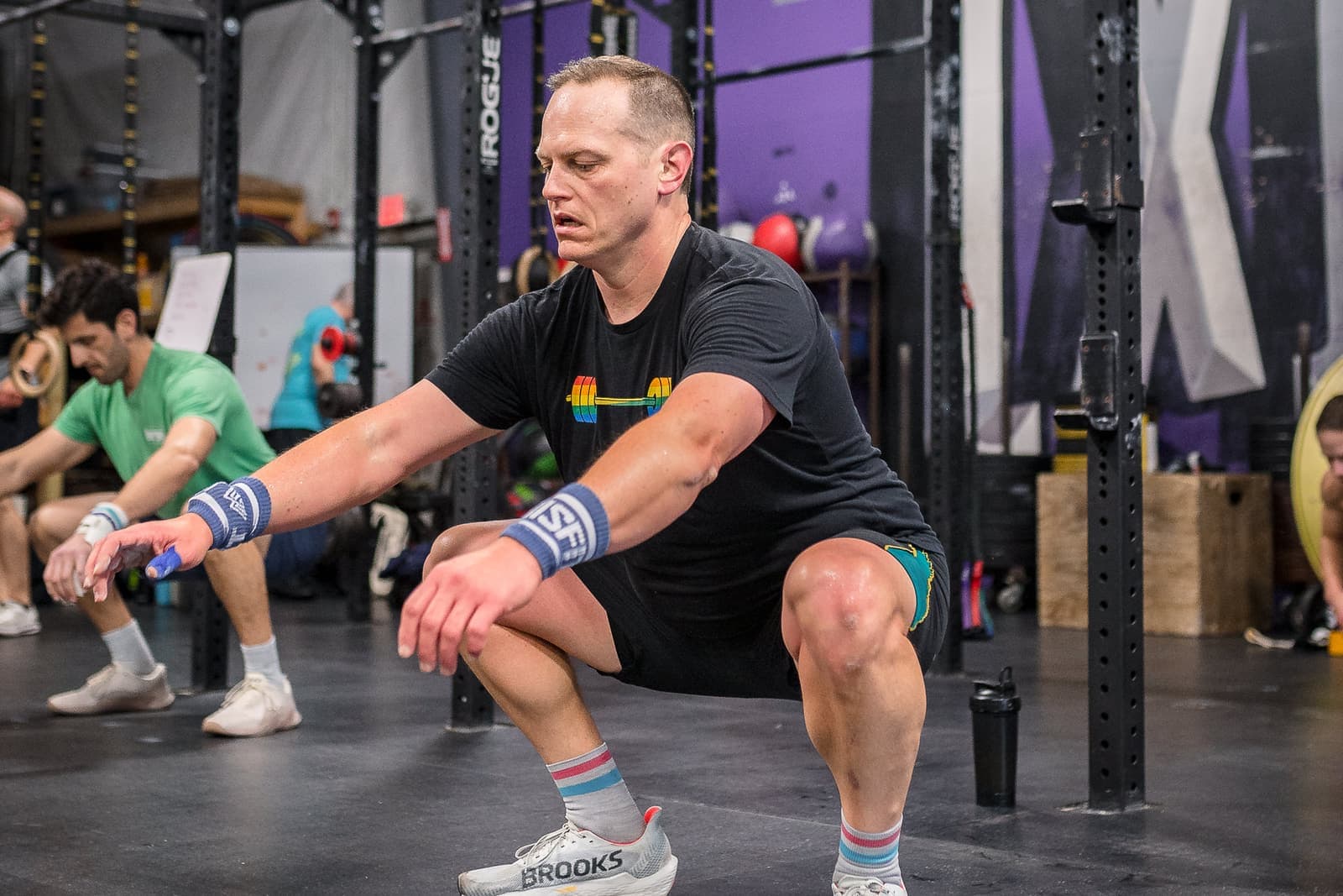 A coach crouched beside a Misfit member, coaching their squat one-on-one