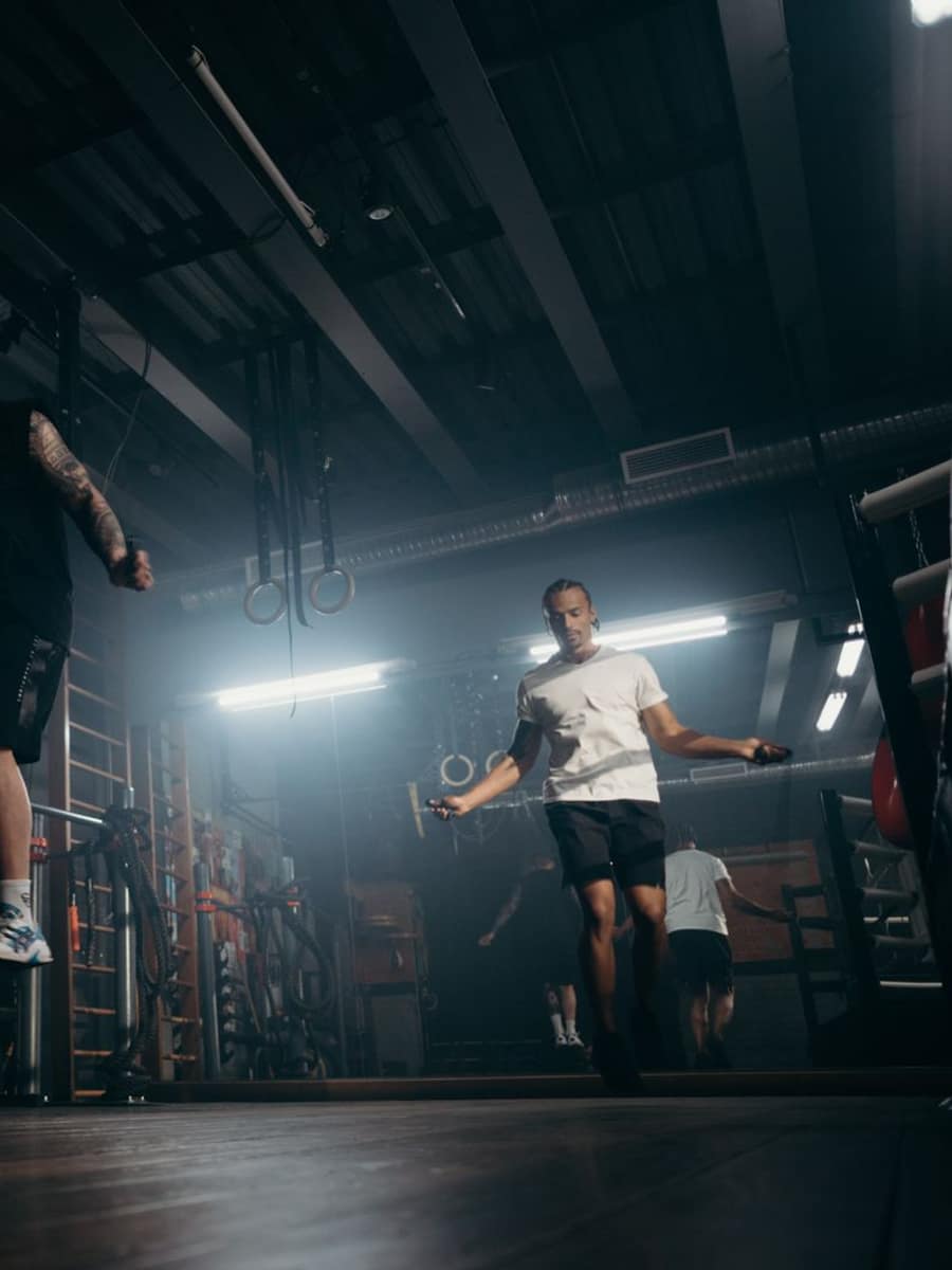 Athlete mid jump rope in a dim gym