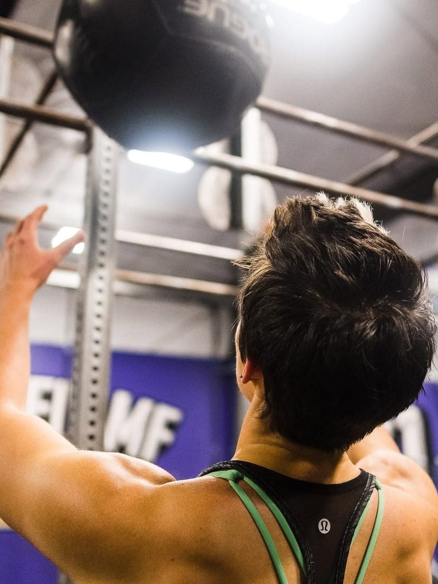 A Misfit member throwing a wall ball up to the target in front of the purple CrossFit MF wall