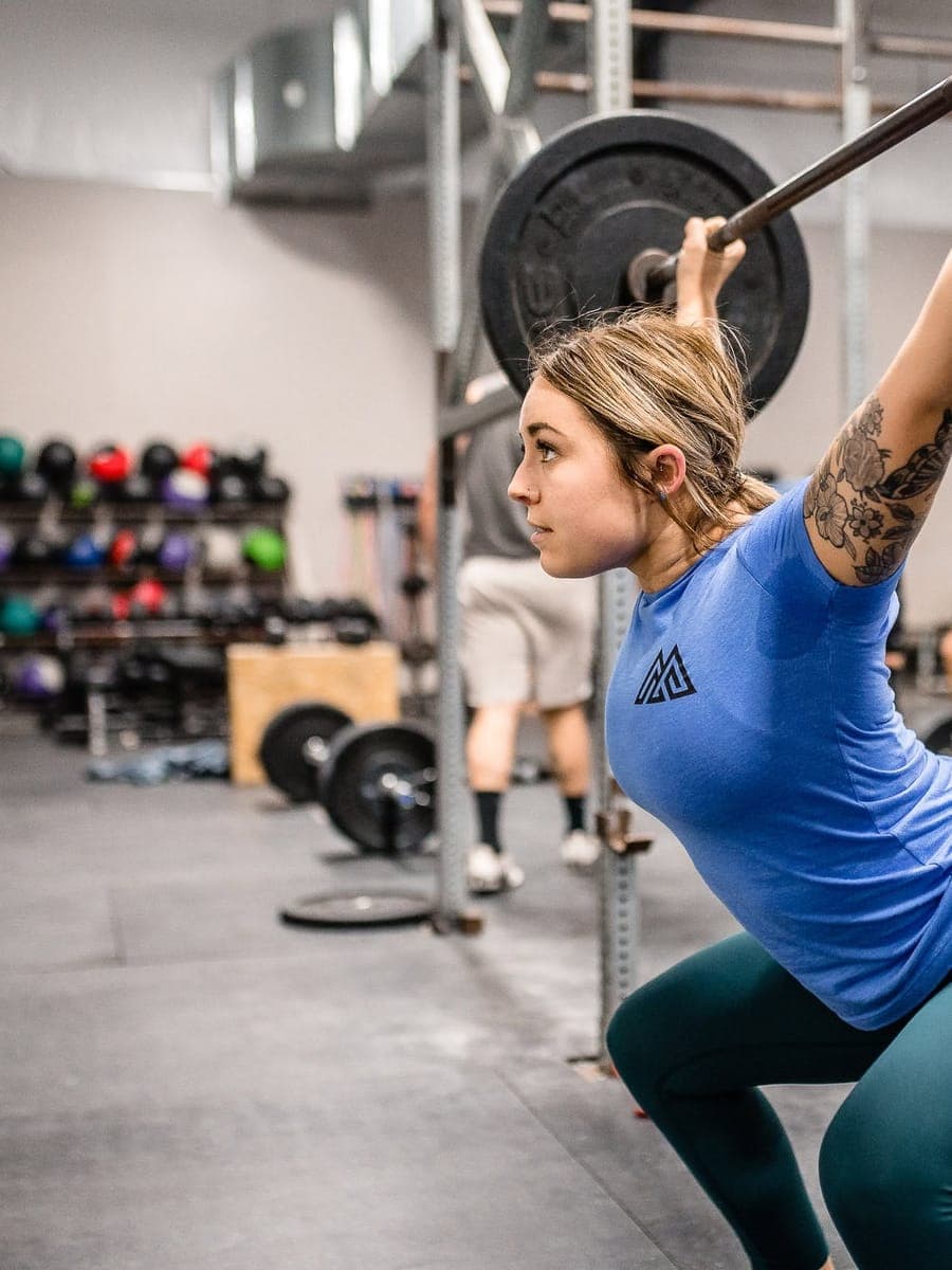 A Misfit member holding the bottom of an overhead squat, barbell locked out overhead