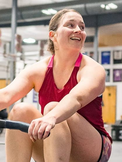 Misfit member smiling mid-stroke on the rowing erg