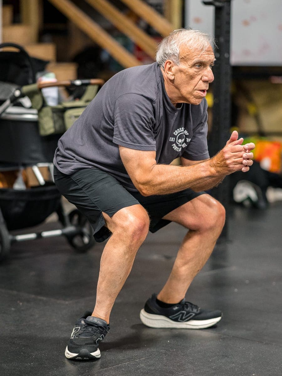 A masters-age Misfit member holding a deep air squat with full range of motion
