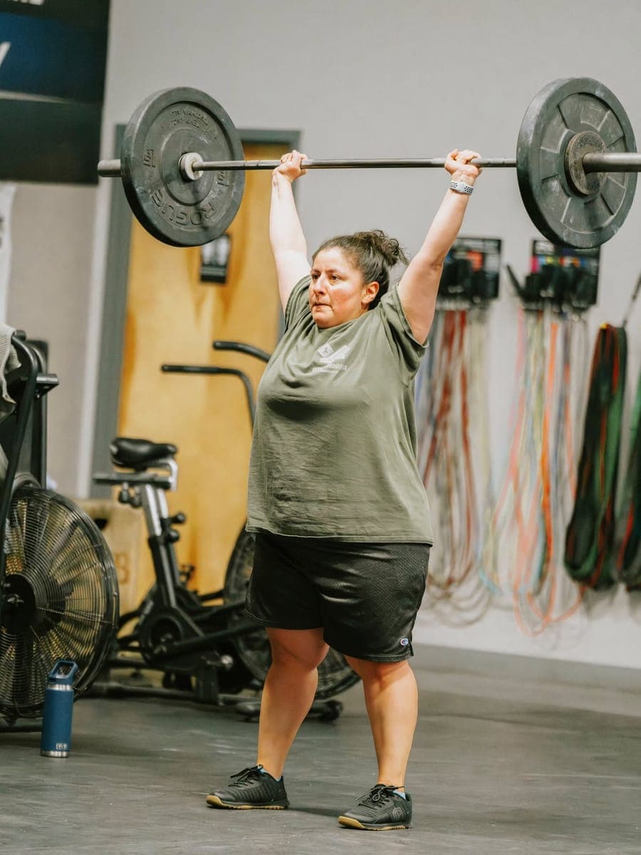 A Misfit member locking out a loaded barbell overhead at the top of a press